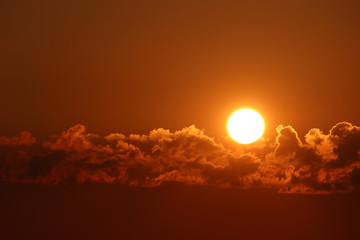 Sunset with clouds, setting shining sun and orange sky. Beautiful skyline for background