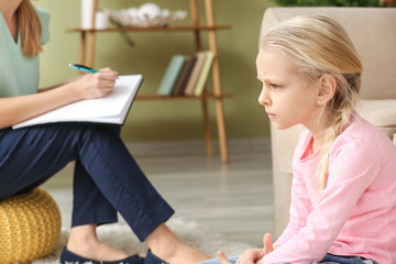 Female psychologist working with little girl in office