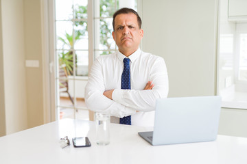 Middle age business man working with computer laptop skeptic and nervous, disapproving expression on face with crossed arms. Negative person.