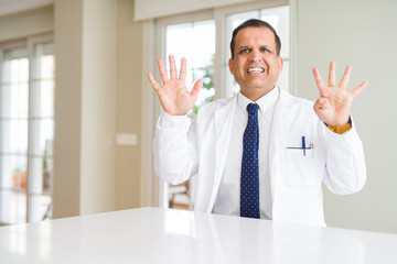 Fototapeta premium Middle age doctor man wearing medical coat at the clinic showing and pointing up with fingers number nine while smiling confident and happy.
