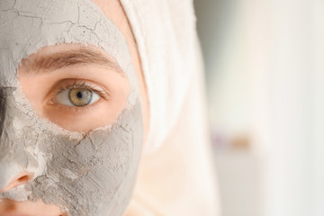 Young woman with clay mask at home, closeup