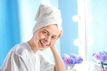 Funny young woman with under-eye patches at home