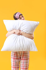 Young woman with pillow and sleep mask on color background