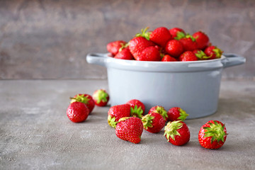 Pot with ripe red strawberry on grey background