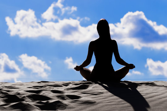 young woman practicing yoga on the beach