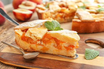 Piece of tasty peach pie on wooden background