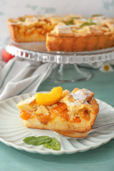 Plate with piece of tasty peach pie on table