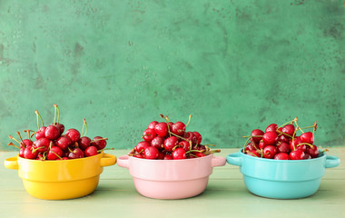 Pots with sweet ripe cherry on wooden table