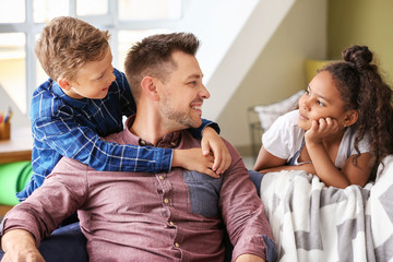 Happy man with little adopted children at home