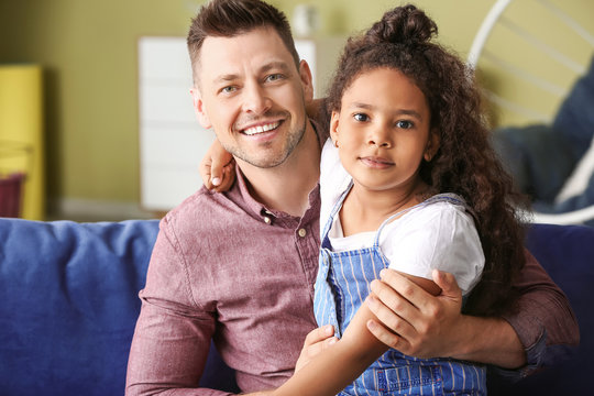 Happy man with little adopted African-American girl at home