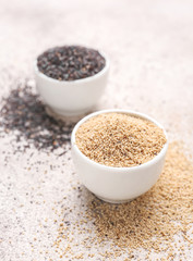 Bowls with different poppy seeds on light background