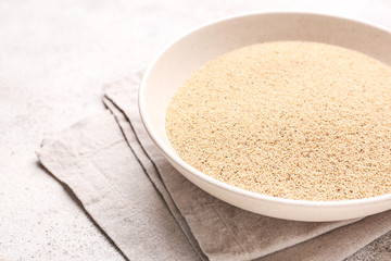Plate with white poppy seeds on light background