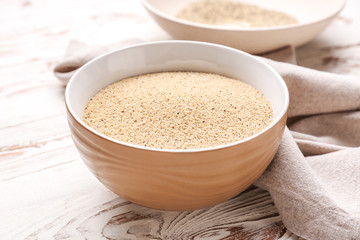 Bowl with white poppy seeds on wooden background