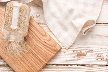 Overturned glass jar with white poppy seeds on wooden table