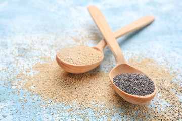 Spoons with different poppy seeds on color background