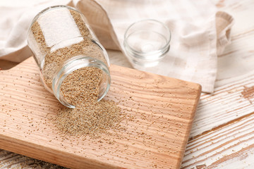 Overturned glass jar with white poppy seeds on wooden table