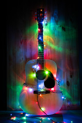 Classic Acoustic Guitar in christmas holiday lights in memory of music. Poster party background with place for text and club or sponsor company logo