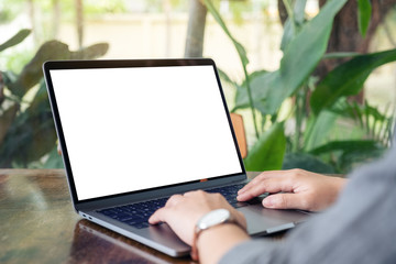 Mockup image of a woman using and typing on laptop with blank white desktop screen on wooden table