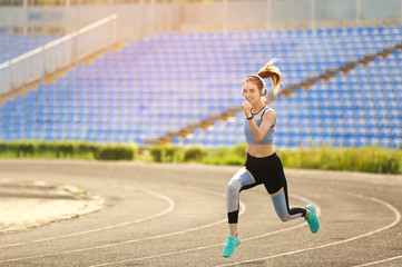 Plakat Sporty young woman running at the stadium