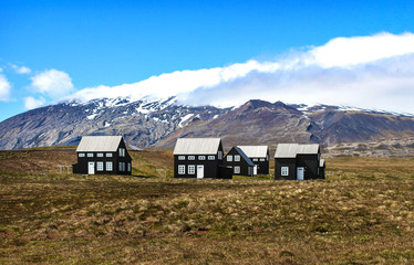 Fototapeta na wymiar Landscape with black houses in Snaefellsnes peninsula with Snæfellsjökull in background / Iceland