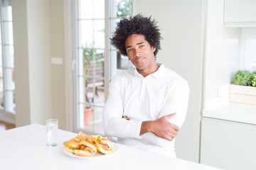 Obraz na płótnie Canvas African American hungry man eating hamburger for lunch happy face smiling with crossed arms looking at the camera. Positive person.