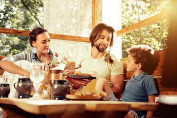 Pleasant cute boy having meal with his family
