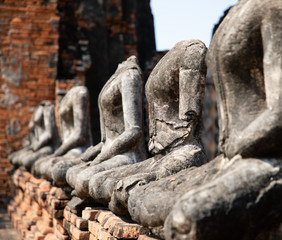 Fototapeta na wymiar Close up of ancient stone buddha statues placed in line in the ruined temple at Ayutthaya