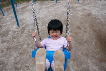 真夏の公園でブランコを遊んでいる子供