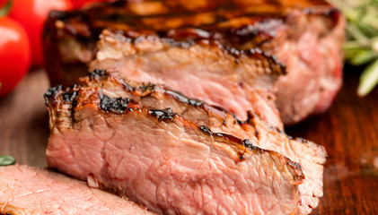 grilled and sliced steak on wooden board