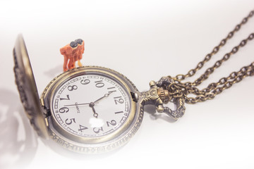 Miniature family with old pocket watch isolated on white background