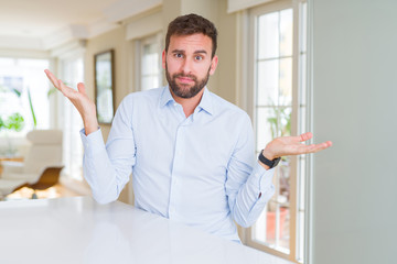 Handsome business man clueless and confused expression with arms and hands raised. Doubt concept.