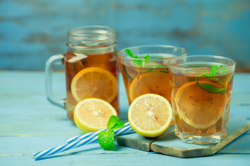 Iced tea with lemon slices and mint on wood background