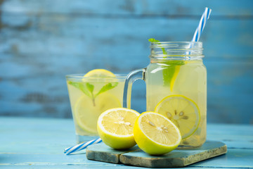 Lemonade or mojito cocktail with lemon and mint on wood background