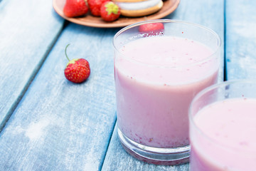 Cocktail with milk and berries club in a glass against the background of blue boards.
