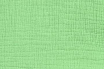 Cotton muslin background in pale green color. Matt fabric surface pressed. Close-up.
