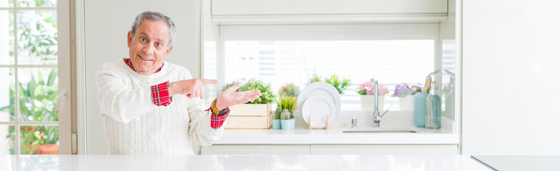 Wide angle perspective of handsome senior man at home amazed and smiling to the camera while...