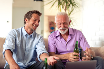 Obraz premium Father and son watch football game on laptop