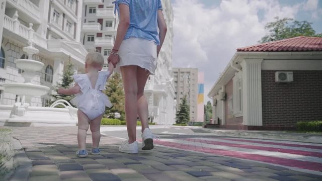 A mother with a baby goes to the fountain in the summer