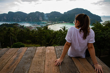 Beautiful woman sitting on wooden platform with Phi Phi island views and cloudy sky