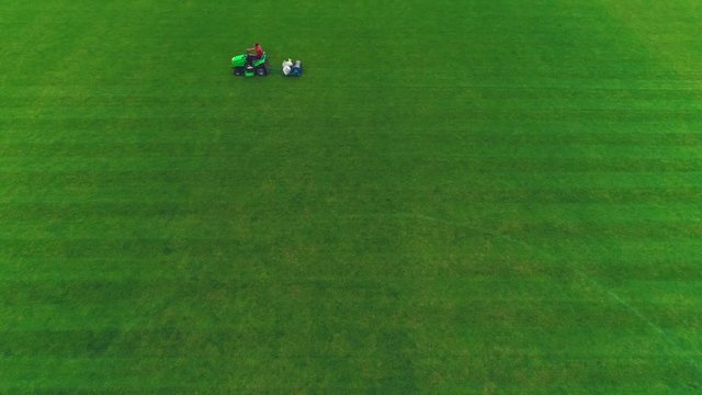 Aerial view of man at his work cutting the football lawn. 4K.
