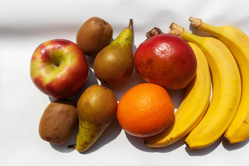 ripe and organic fruits on a white tablecloth on a bright sunny day. ripe fresh fruitS prepared for making smoothies and juiceS. Fruits diet and Healthy nutrition concept.