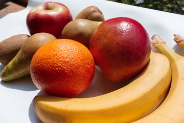 ripe and organic fruits on a white table on a bright sunny day. ripe fresh fruits prepared for making smoothies and juices. Fruits diet and Healthy nutrition concept.