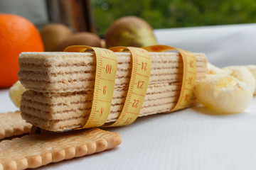 tape measure encircles two waffles as a symbol of diet and Weight lost. the problem of overweight and diabetes, the cause of which is in flour products and sugar.