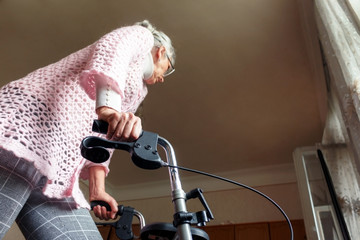 Caucasian middle-aged woman using a walker at home to help her mobility. Focus is on the right hand.