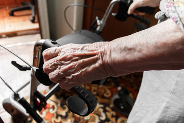 close-up wrinkled hand with veins of an elderly woman holding bar, walk training of a stroke patient at home.