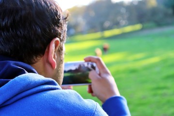 Handsome man taking nature landscape photos with his mobile - Technology use in nature concept