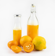 still life photo of orange juice, orange smoothie in glass bottles on white background.