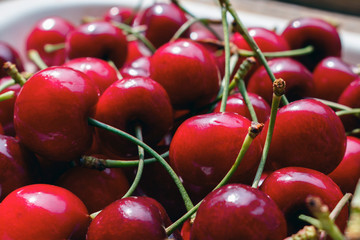 Close up of pile of ripe cherries with green stalks, selective focus. cherry and sweet cherry harvest season