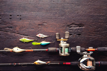 Fishing lures, hooks and accessories on darken wooden background.Top view.