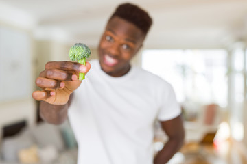 Close up of african american man holding fresh broccoli as healthy food
